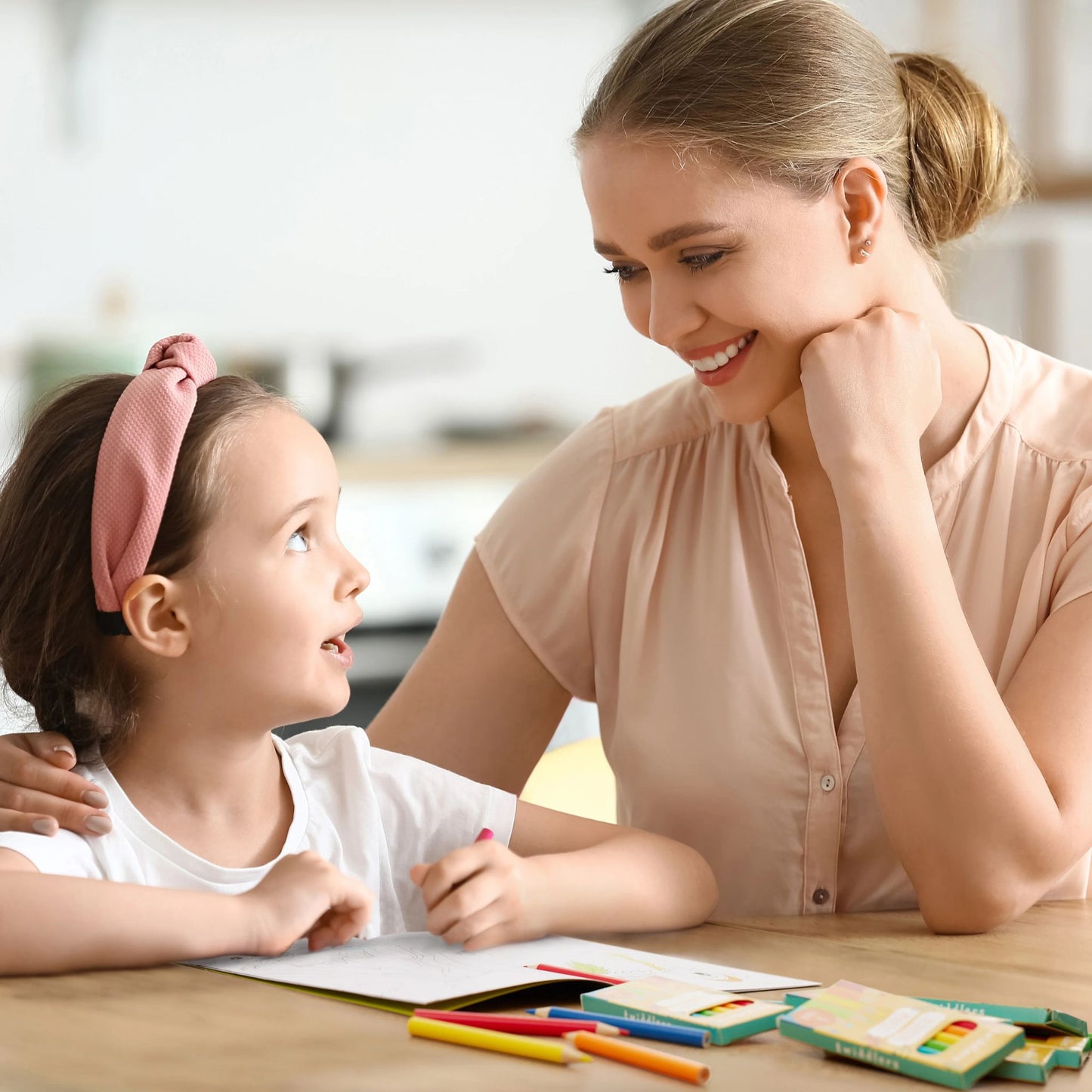 Mother and child colouring together with a small 6 pack of pencils on the table