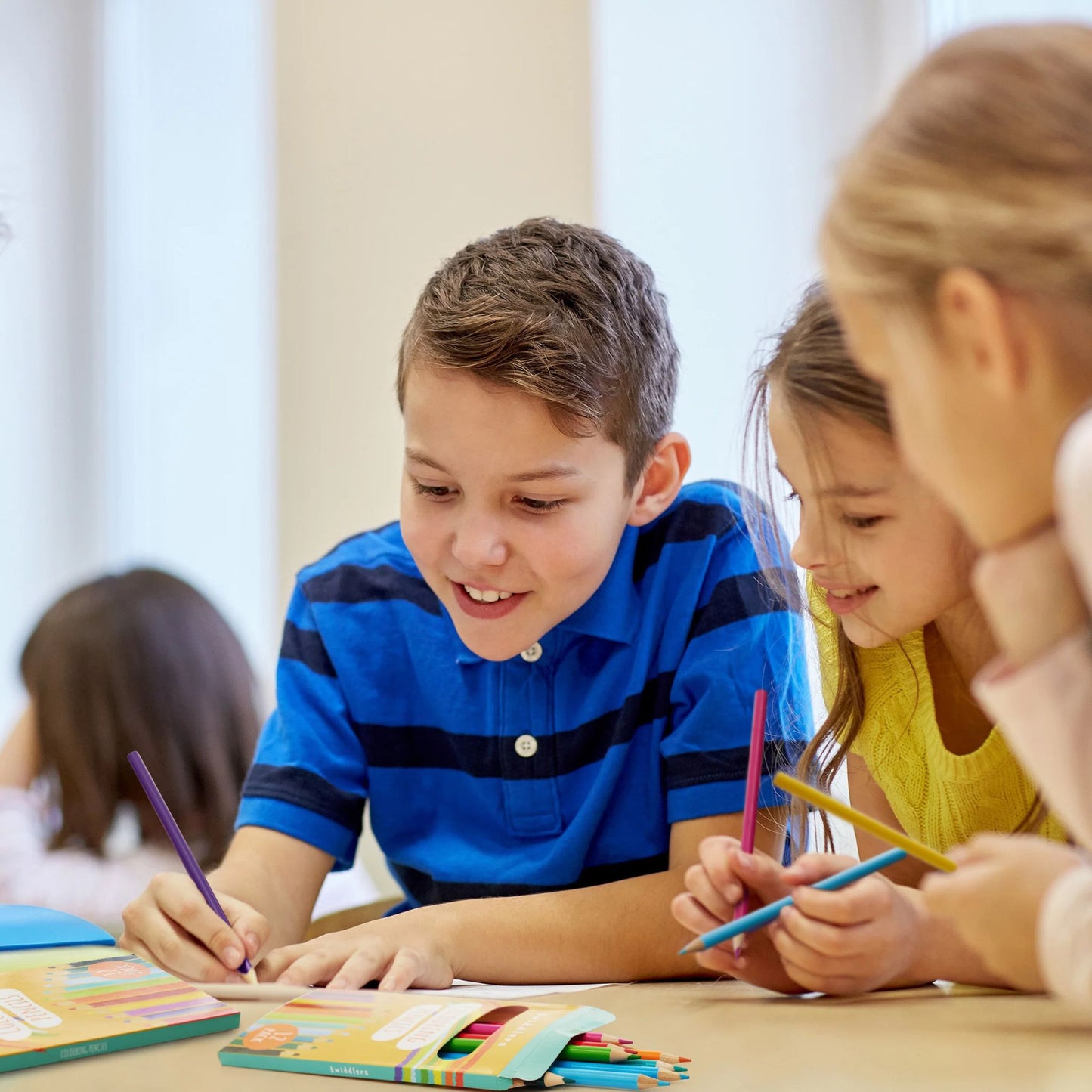 Children colouring with 12-pack colouring pencils at a classroom table, smiling and engaged in creative play