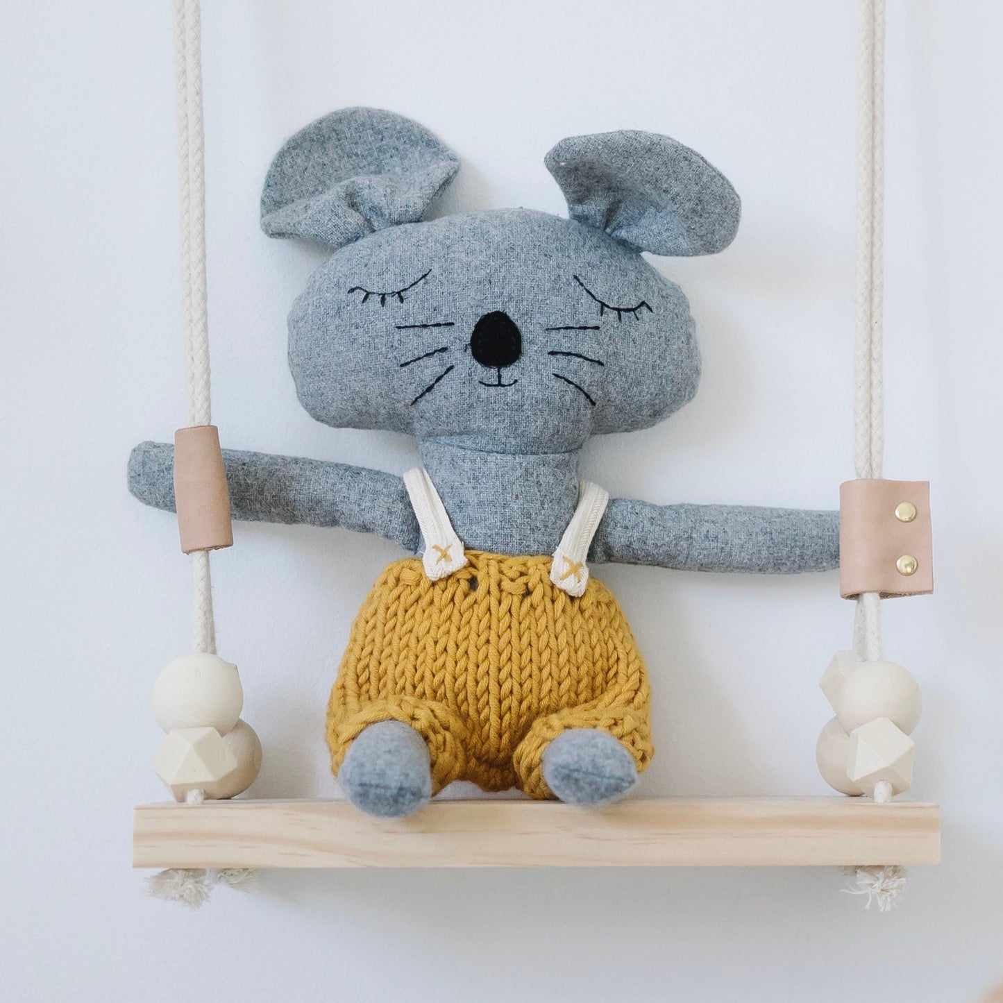 Soft plush mouse toy with knitted mustard shorts sitting on wooden swing – Mamutino