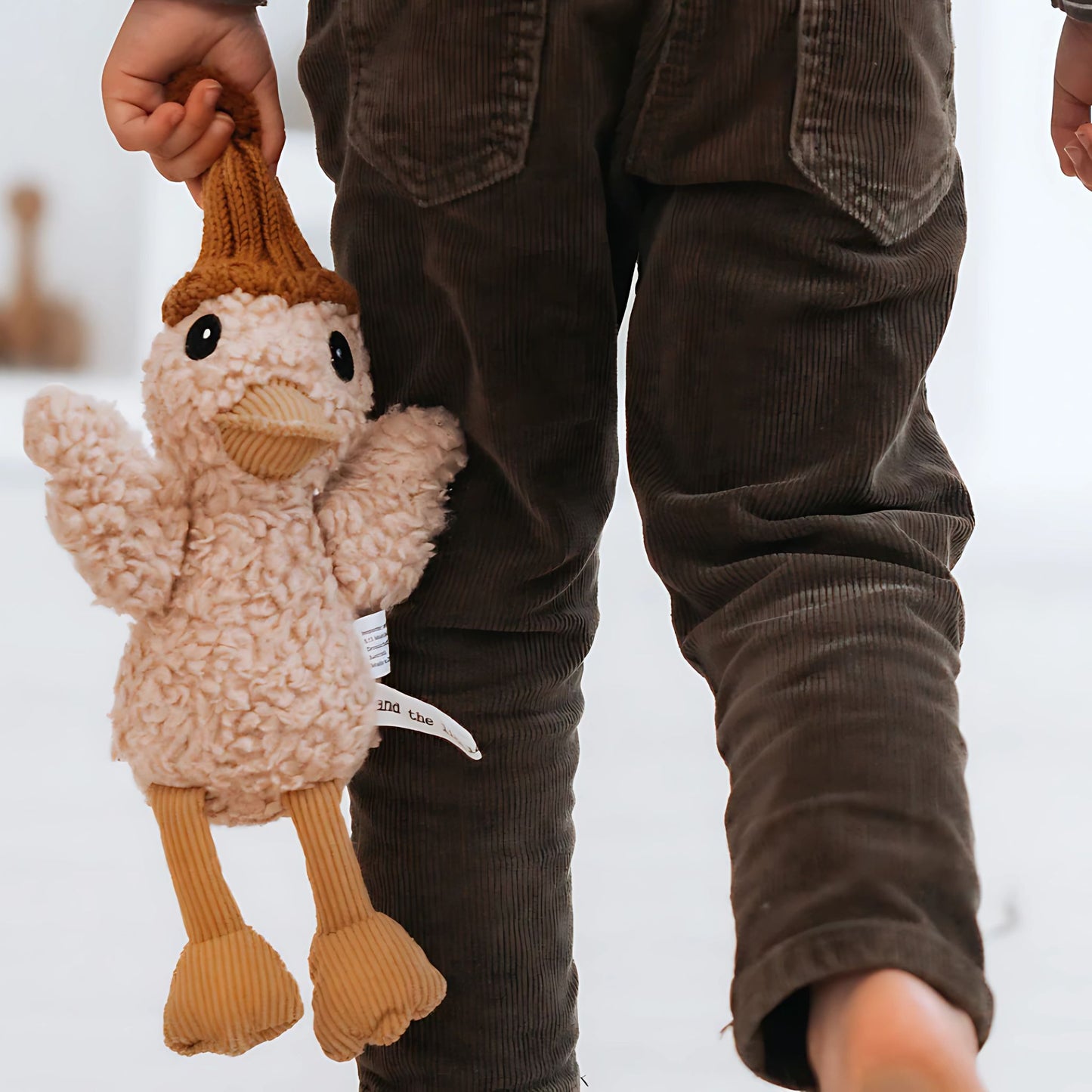 Child holding cotton plush duck toy with mustard knit beanie – Mamutino
