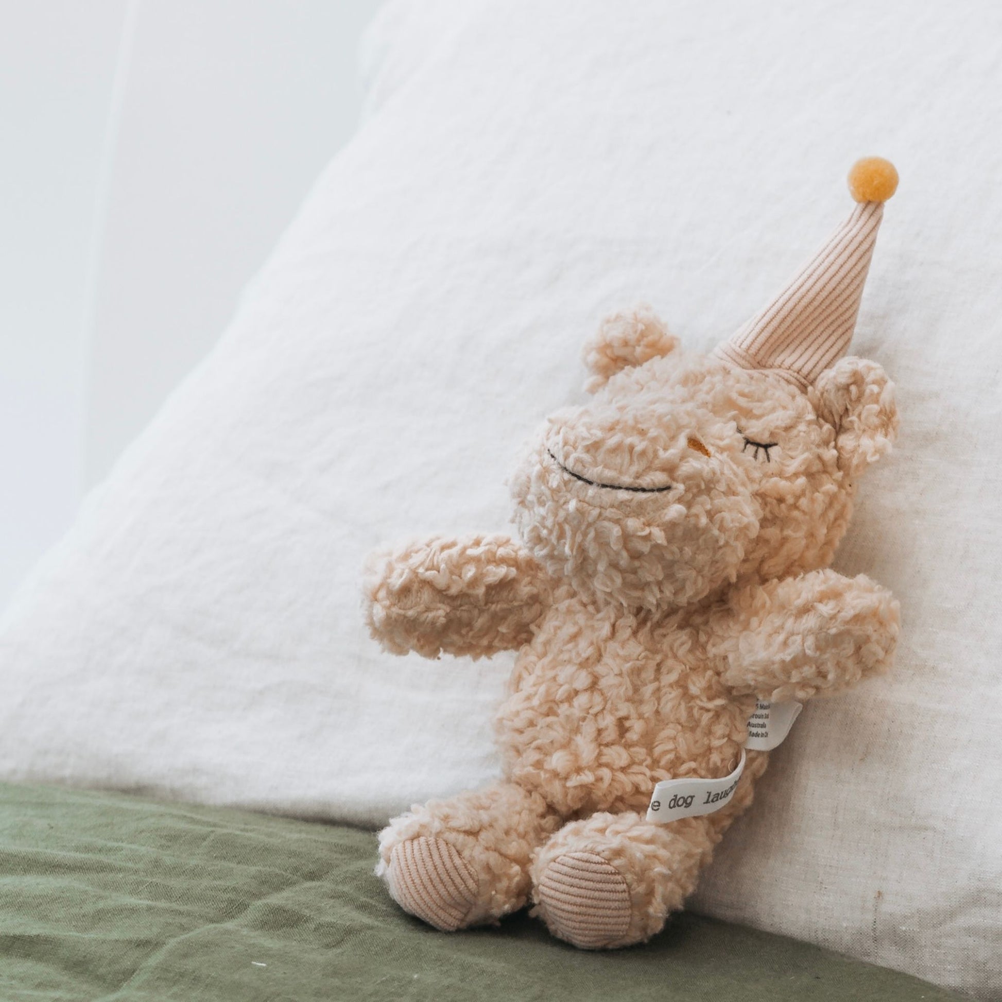 Soft cotton plush hippo toy with pink hat and mustard pom-pom on a cushion – Mamutino