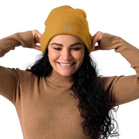 Model wearing ribbed knit beanie hat in mustard yellow with embroidered coffee cup design, front view