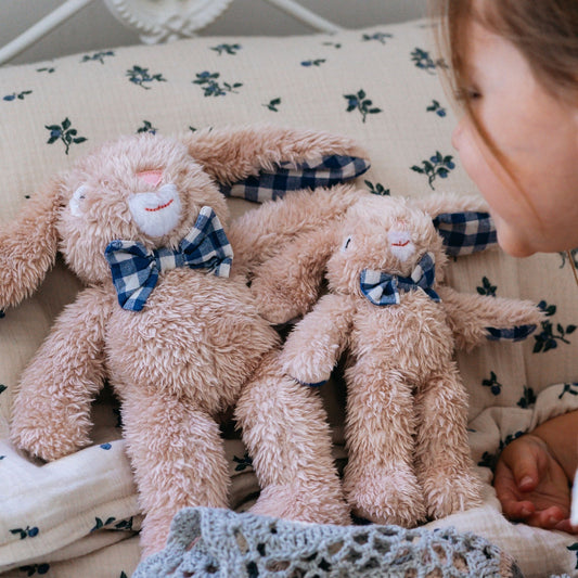 Group of small plush rabbits with blue gingham bows on nursery bedding – Mamutino