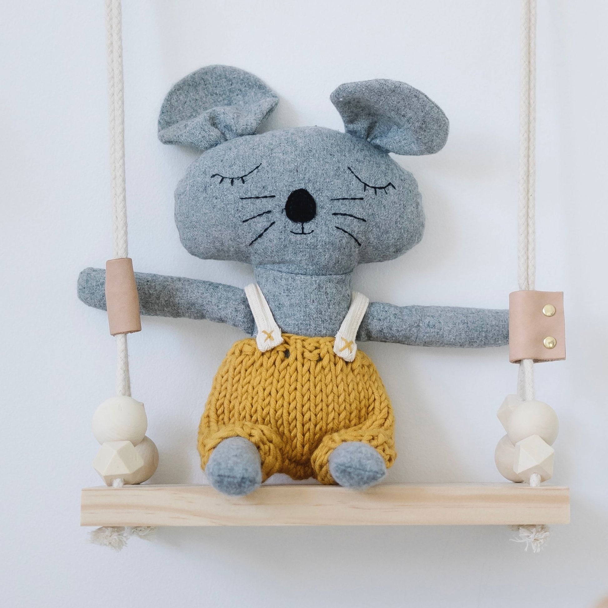Soft plush mouse toy with knitted mustard shorts sitting on wooden swing – Mamutino
